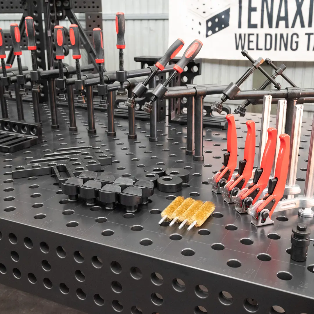 A complete set of Tenaxis welding table toolkit, including professional toggle clamps, v-cross supports, and fixtures arranged on a modular cast iron table.