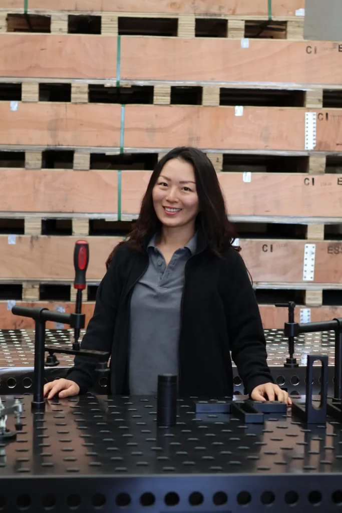 Natalie, Co-founder and Operations head, standing with a CNC-machined modular welding fixture table.