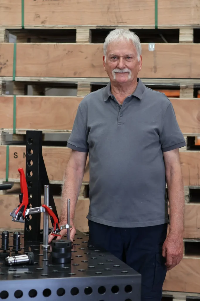 Ross, Advisor and Mentor to both Ray and Natalie, standing with a CNC-machined modular welding fixture table.