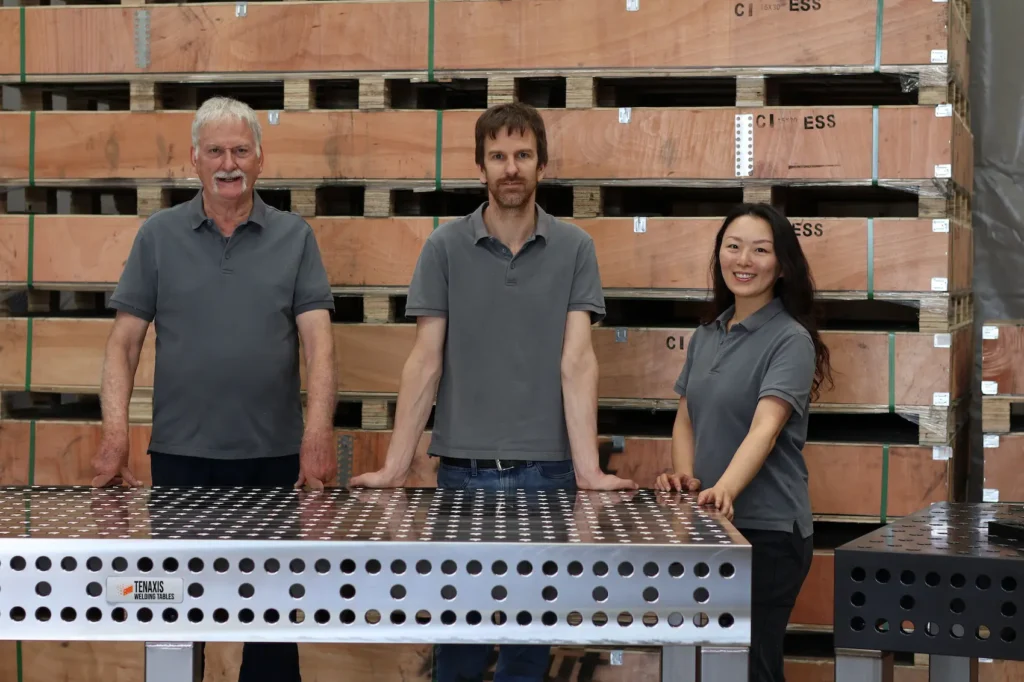 The Tenaxis Canada team standing with a professional System 28 modular welding fixture table in a warehouse environment.