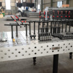 Close-up view of a raw cast iron welding table with a professional fixture kit
