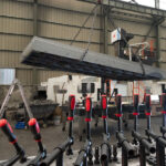 Industrial crane lifting a 1500x3000mm raw cast iron welding table top