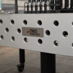 Close-up view of tenaxis logo on a raw cast iron welding table