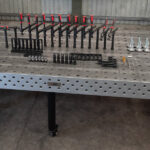 Front view of a 1500x3000mm ESS raw cast iron welding table with a professional fixture and clamp kit.