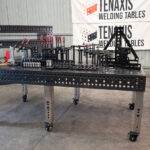 Front view of a 1200x2400mm nitrided steel welding table with a professional fixture kit and stainless steel adjustable legs.