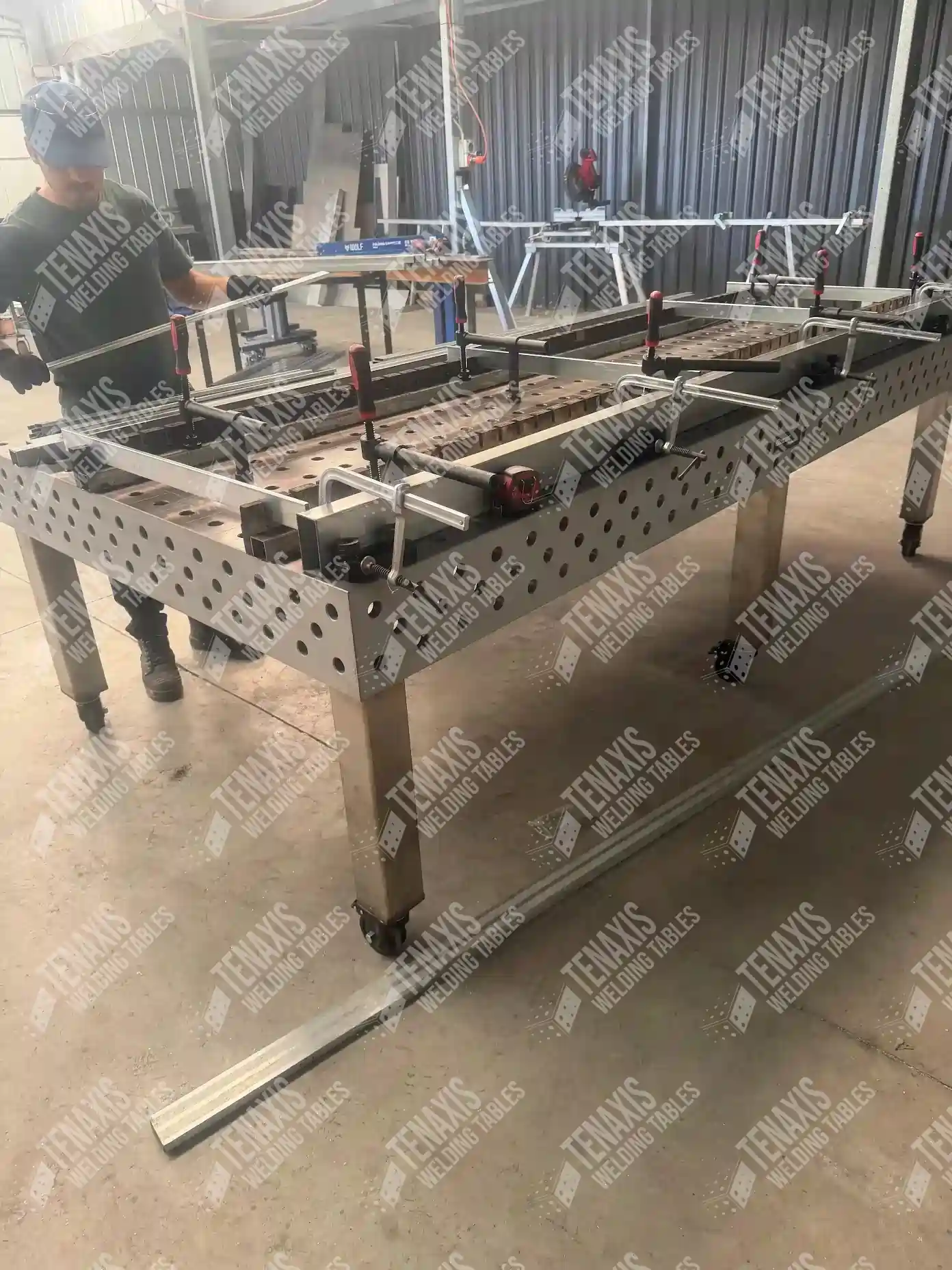 A professional workshop utilizing a mobile welding table with leveling casters, and fixtures for a custom steel project.